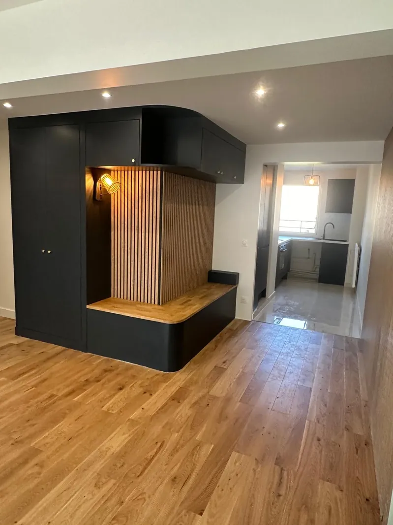 Meuble d'entrée sur mesure réalisé par Renovaurea : finition noire, assise en chêne massif et panneau cannelé rétroéclairé